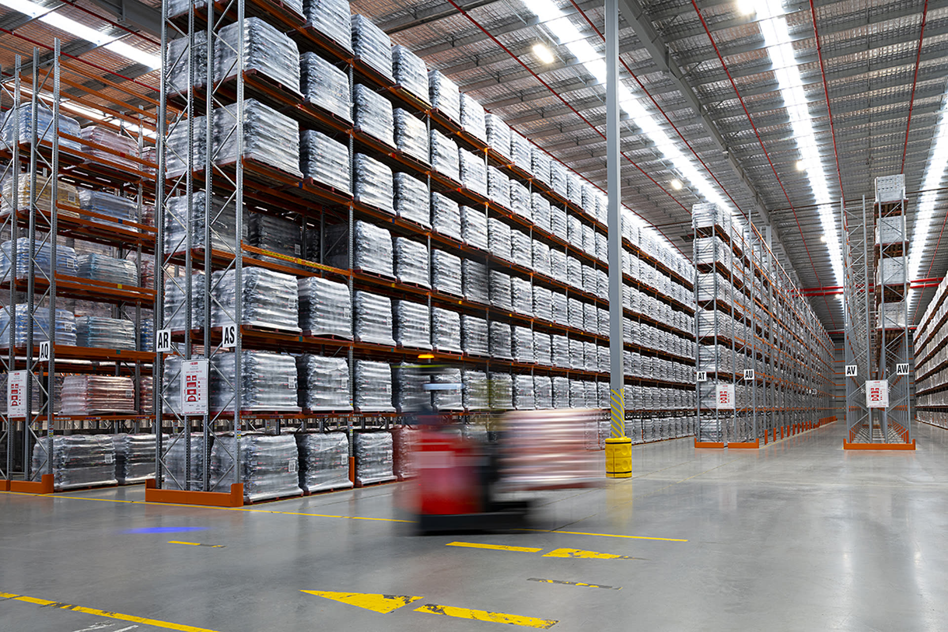 High-bay pallet racking inside the TWL Kemps Creek warehouse with a forklift moving stock along the aisle